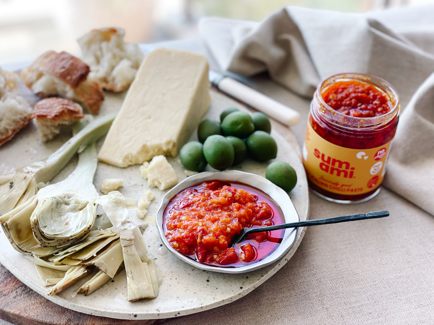 Sumami Italian Chilli Paste elegantly displayed on a cheese platter, featuring a rich red color and accompanied by slices of sourdough bread, perfect for gourmet entertaining.