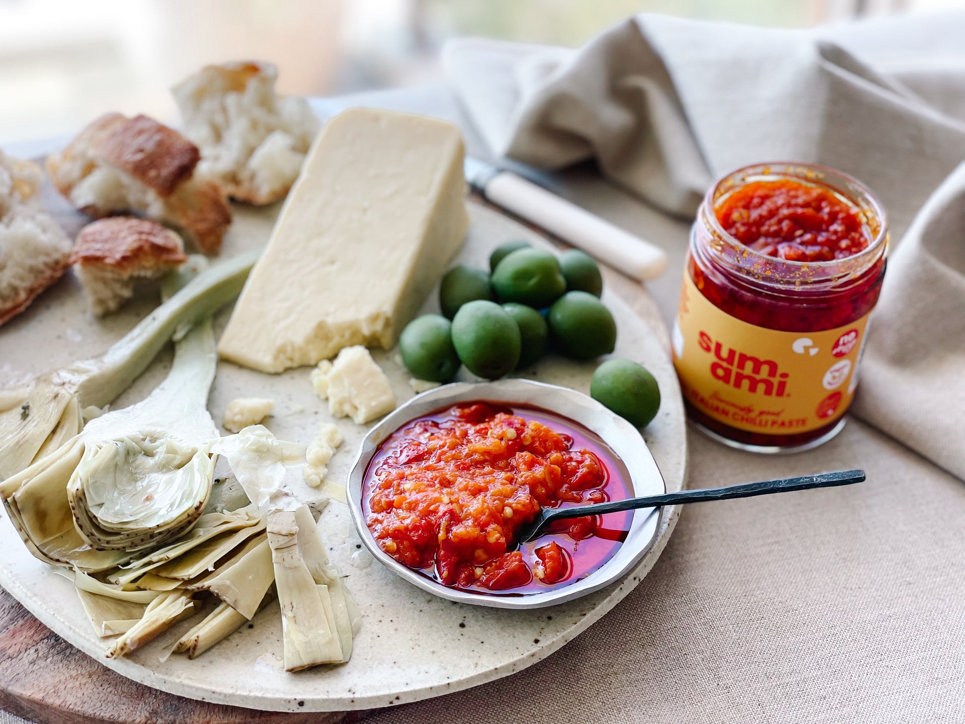 Sumami Italian Chilli Paste elegantly displayed on a cheese platter, featuring a rich red color and accompanied by slices of sourdough bread, perfect for gourmet entertaining.